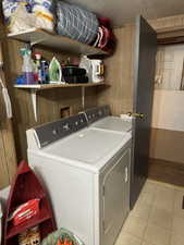 Laundry area featuring wooden walls and washing machine and clothes dryer