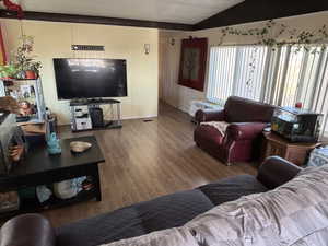 Living room with wood finished floors, lofted ceiling, and radiator heating unit