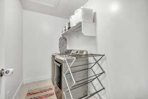 Laundry room featuring washer and dryer and light tile patterned flooring