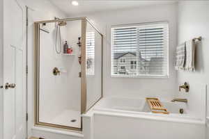 Bathroom with a stall shower, plenty of natural light, and a garden tub