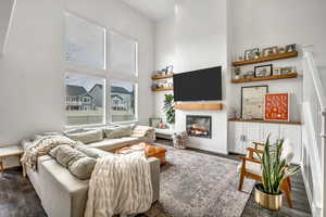 Living area with a high ceiling, dark wood-style floors, and a brick fireplace