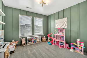 Recreation room with a decorative wall, carpet flooring, and hanging lights