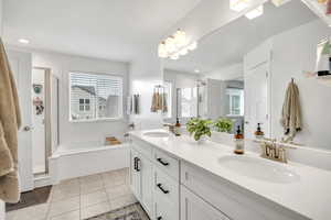 Full bathroom with a shower stall, double vanity, healthy amount of natural light, a garden tub, and recessed lighting