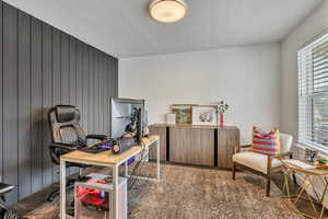 Office space featuring wood walls, wood finished floors, and a textured ceiling