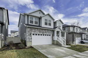 Craftsman house featuring a garage, stone siding, concrete driveway, a residential view, and a gate