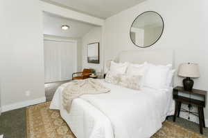Bedroom with light carpet, vaulted ceiling with beams, and a closet