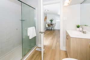 Full bathroom featuring a stall shower, vanity, and light wood finished floors