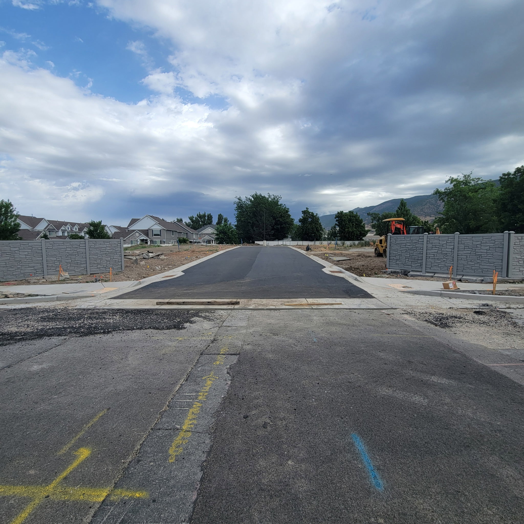 Newly paved asphalt roadway leading into a developing community