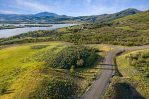 Paved road winding through expansive green and brush-covered terrain