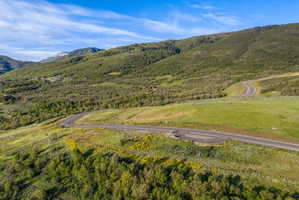 Expansive mountainous landscape featuring green hillsides and scattered trees