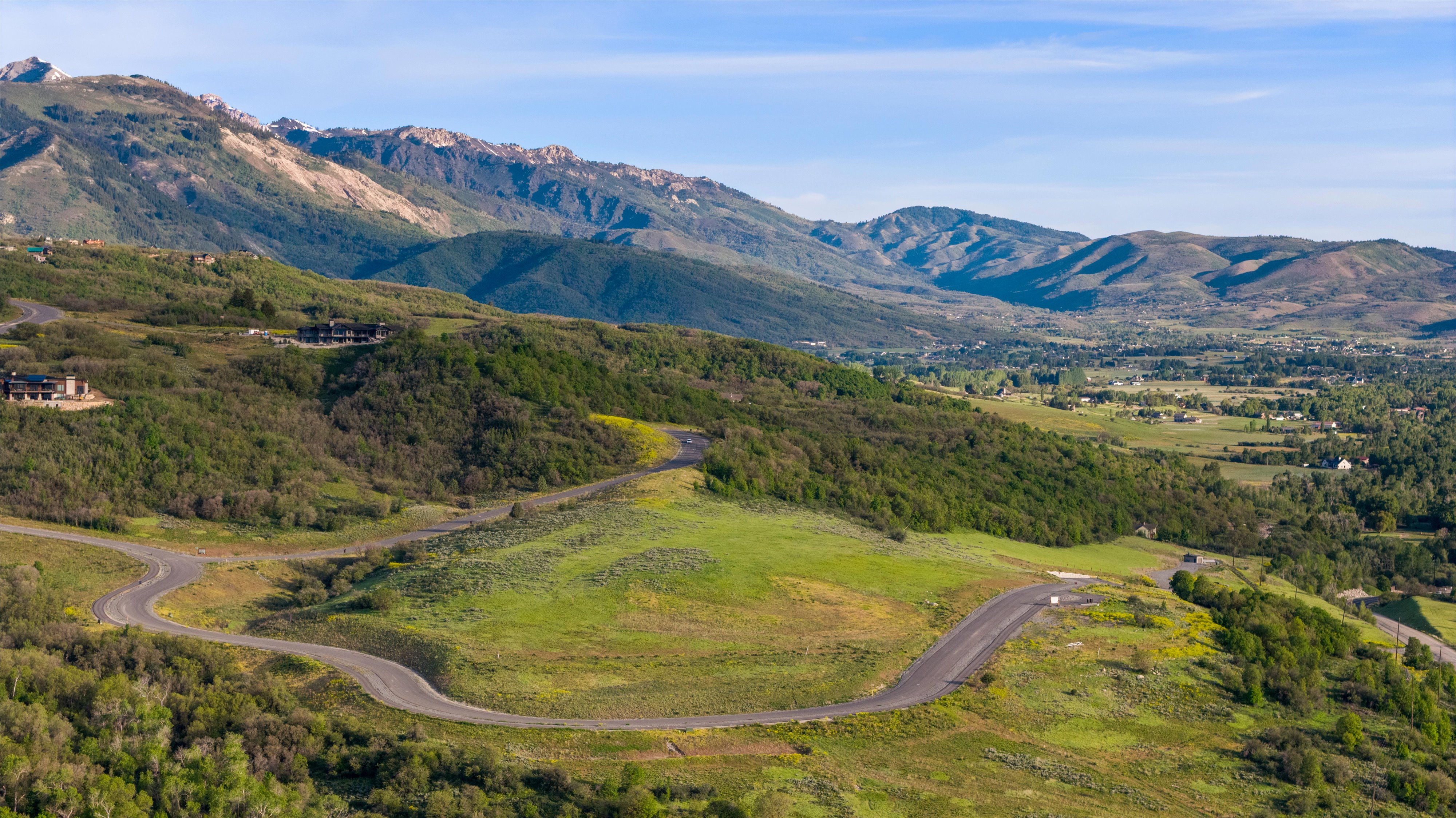 Winding paved road ascending through green hillside terrain