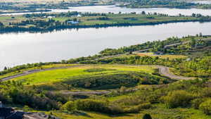 Expansive water body with verdant tree-lined shores, surrounded by agricultural fields and distant hills