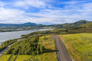 Expansive land parcel featuring a paved road, natural green landscaping, and distant water views