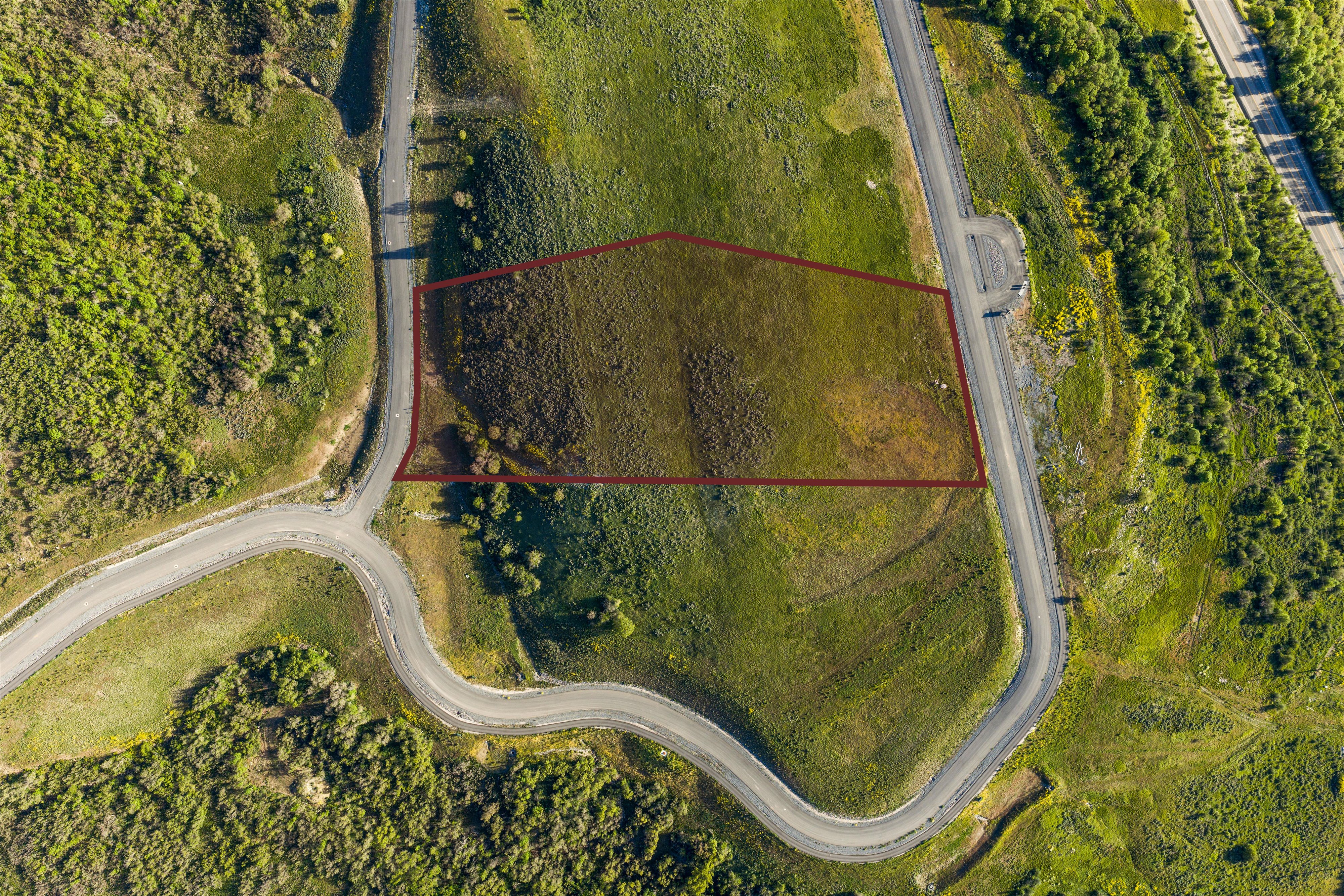 Expansive land parcel featuring natural topography, established road frontage, and surrounding green spaces