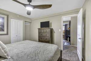 Carpeted bedroom with a closet and a ceiling fan