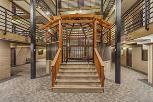 Stairway featuring a towering ceiling, brick wall, and carpet floors