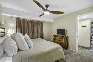 Bedroom featuring light stone finish floors, light colored carpet, a ceiling fan, and stainless steel fridge