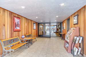 Building lobby with wood walls, a wall of windows, a textured ceiling, and recessed lighting