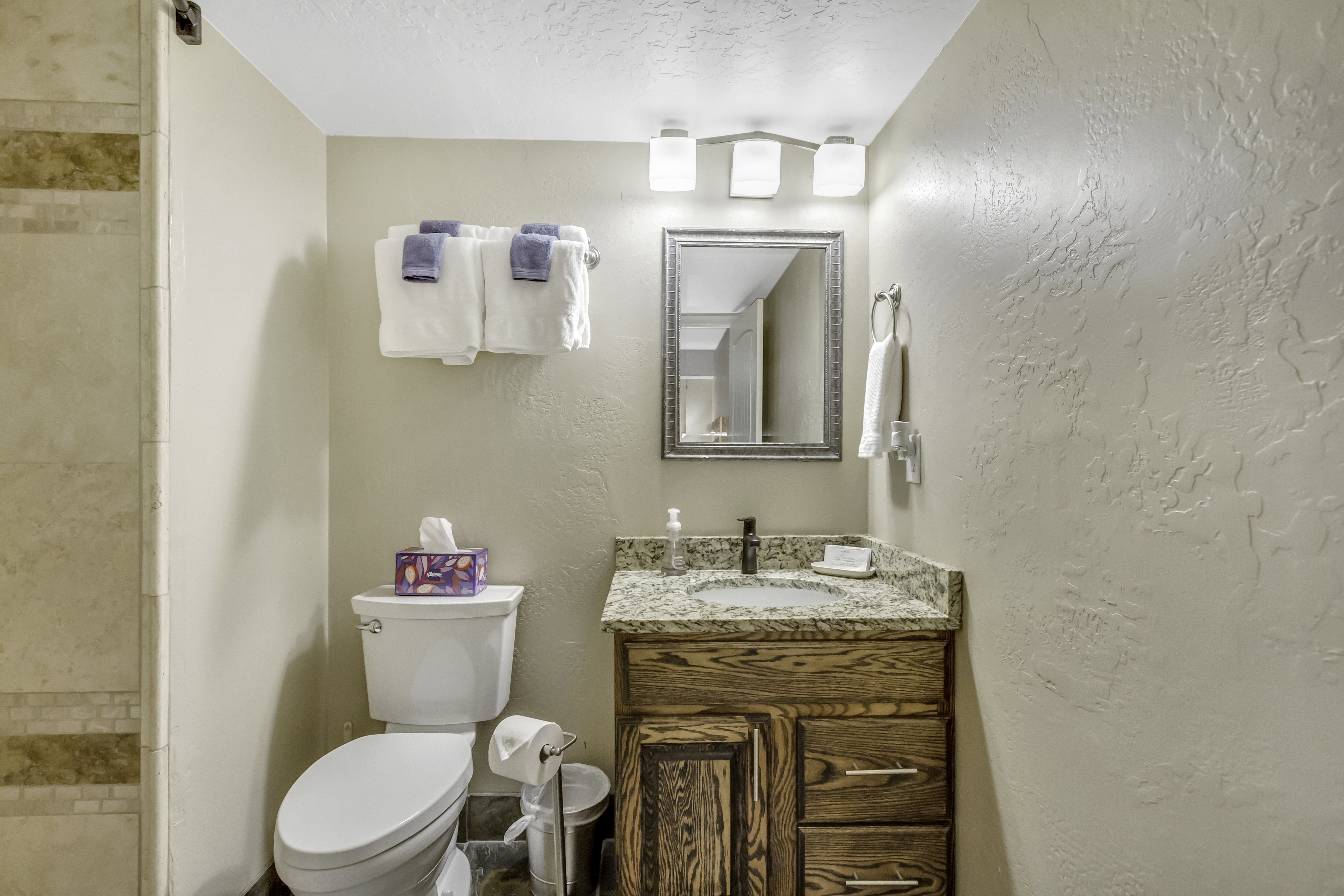 Bathroom with a textured ceiling, vanity, a textured wall, and tiled shower