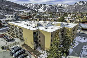 Snowy aerial view with a mountain view and a view of apartment building / complex