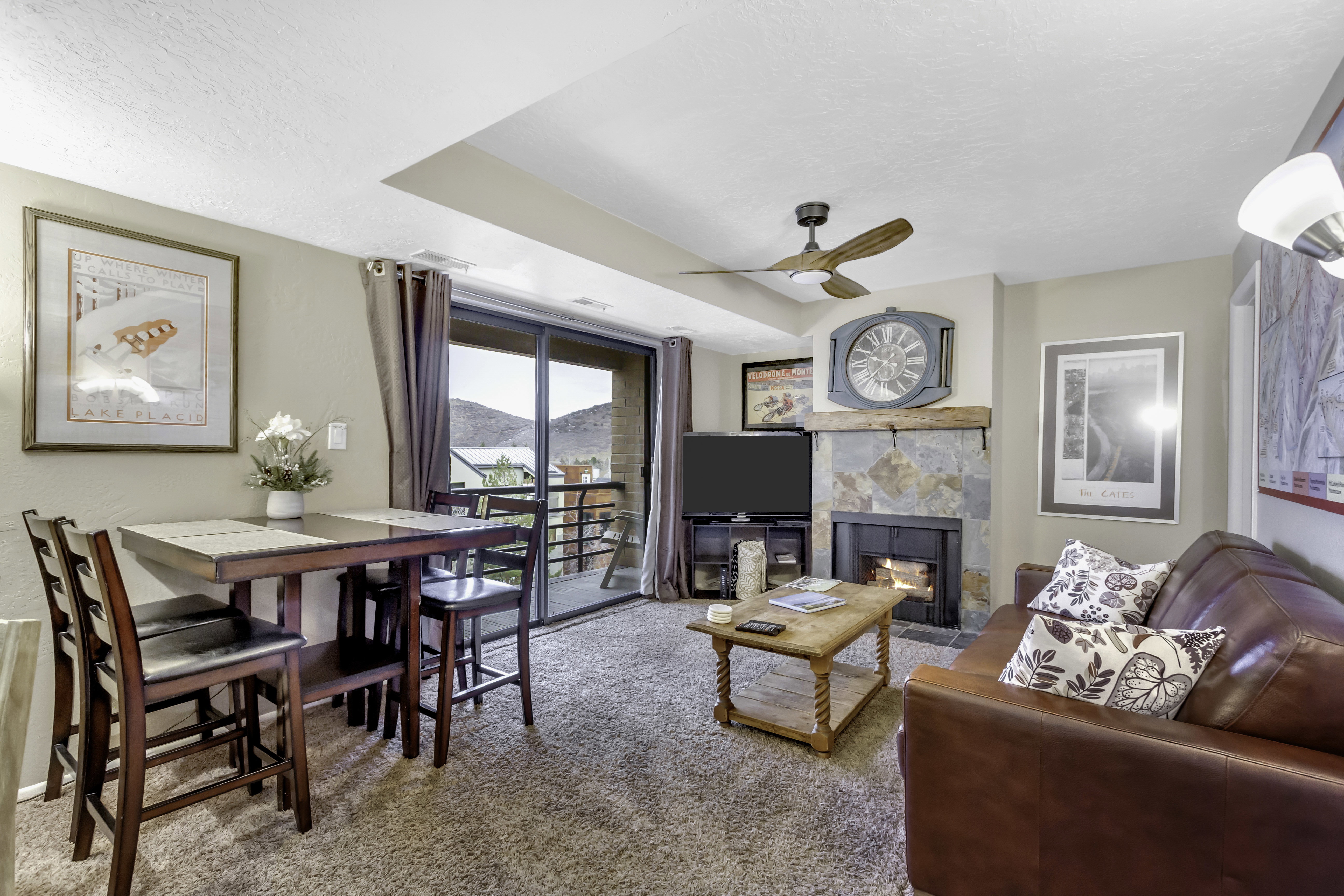 Living room with a tile fireplace, light colored carpet, ceiling fan, and a textured ceiling