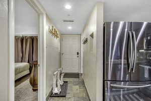 Hallway featuring light stone finish floors and recessed lighting