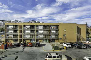 View of apartment building / complex with a mountain view and uncovered parking