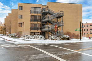 Snow covered building featuring a view of apartment building / complex