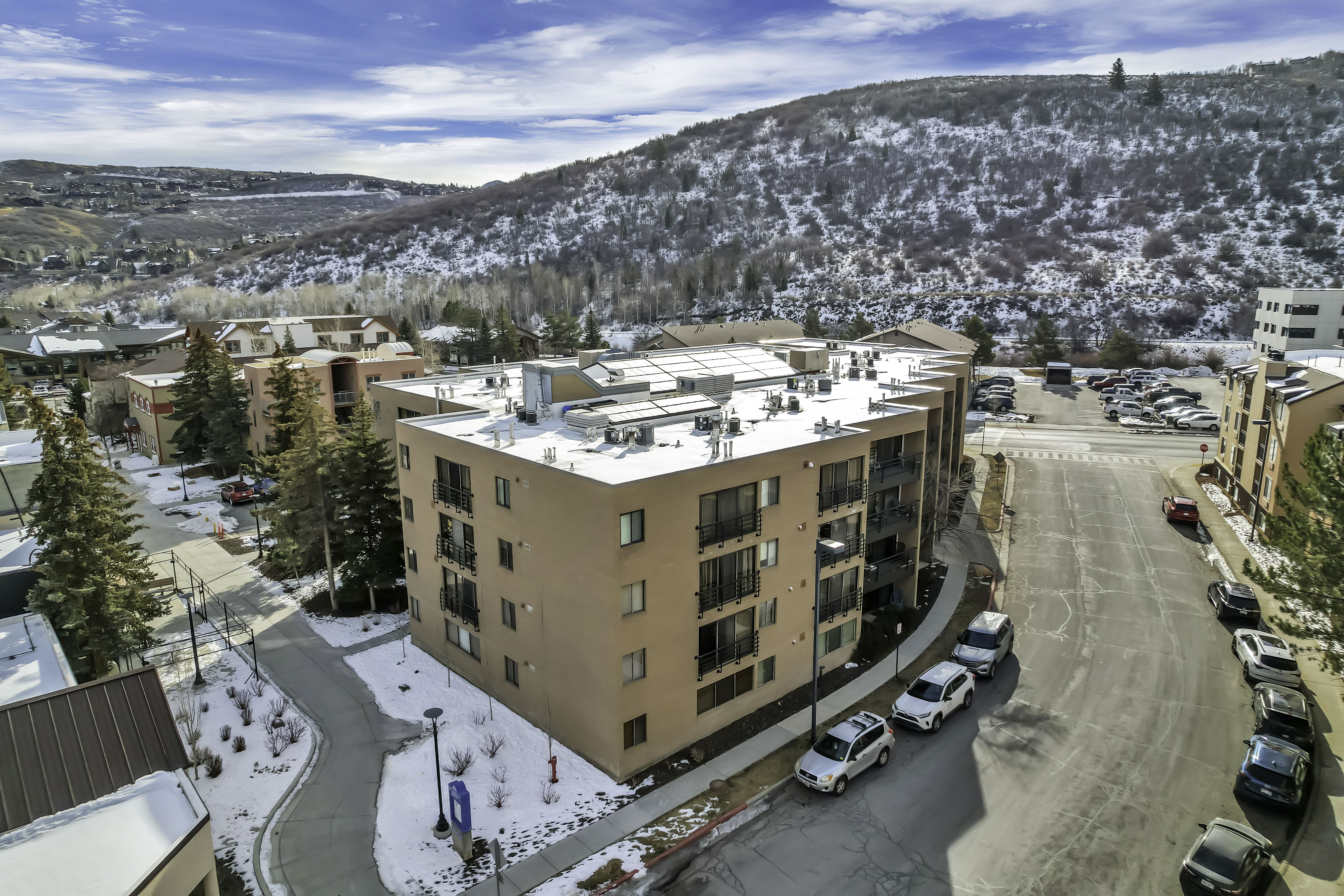 Snowy aerial view featuring a mountain view and a view of apartment building / complex