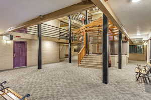 Finished below grade area with stairs, carpet flooring, brick wall, and a textured ceiling