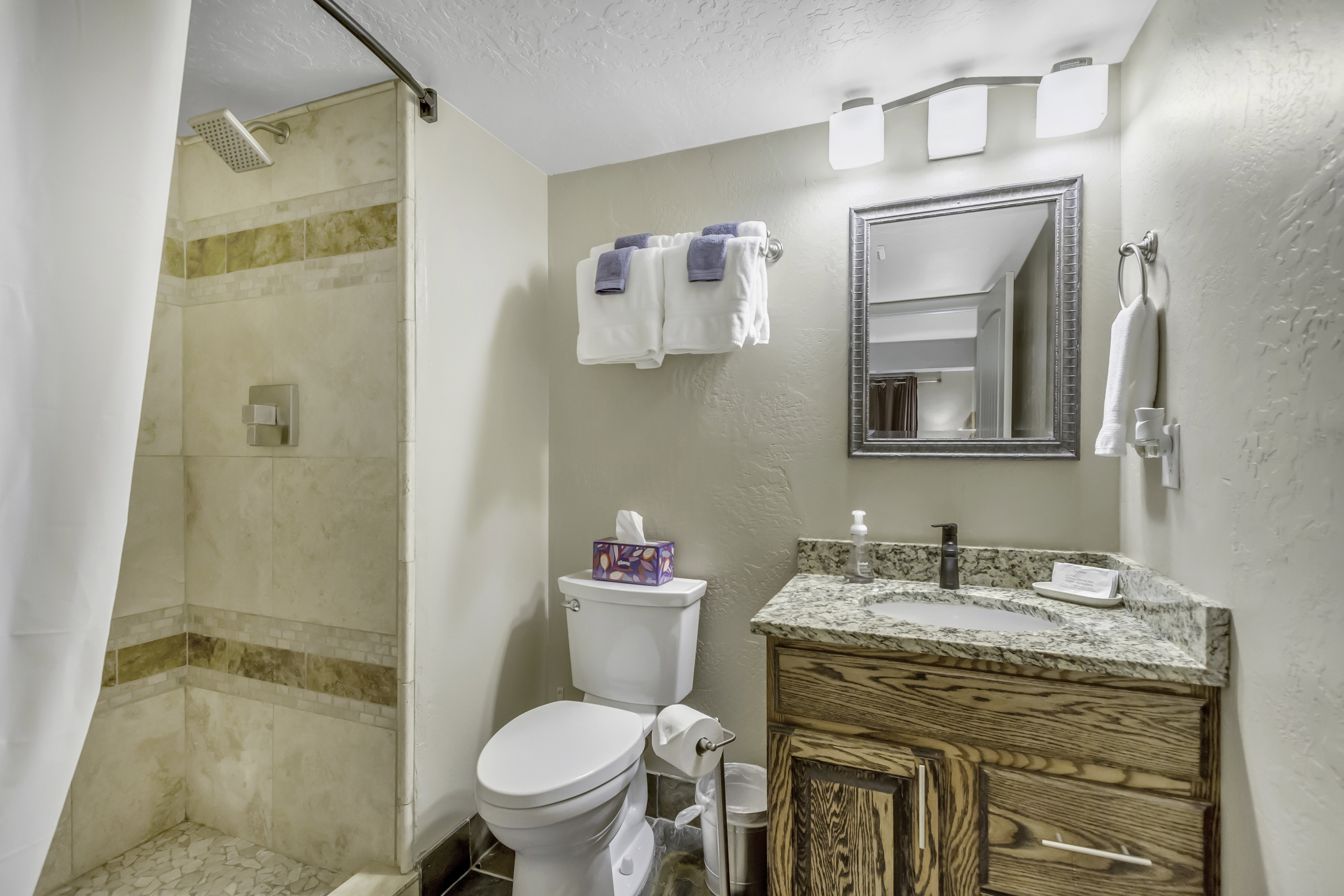 Bathroom with a shower stall, vanity, a textured ceiling, and a textured wall