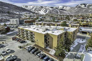 Snowy aerial view featuring a mountain view and a view of apartment building / complex