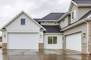 View of front of house with roof with shingles, board and batten siding, and stone siding