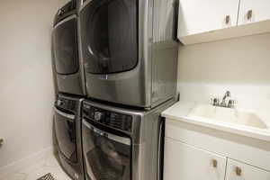 Laundry room with cabinet space, stacked washer / dryer, and tile patterned flooring