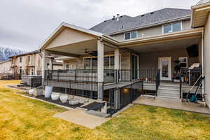 Back of house featuring a patio area, a shingled roof, a ceiling fan, and a lawn