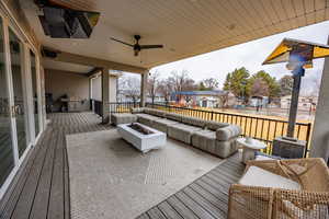 Deck featuring an outdoor living space with a fire pit, ceiling fan, grilling area, and a residential view
