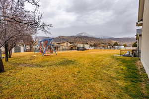 Fenced yard with a playground, a mountain view, and a residential view