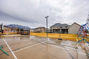 View of sport court featuring a trampoline, a playground, and a residential view