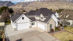 View of front of property featuring board and batten siding, stone siding, roof with shingles, a mountain view, and driveway