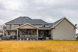 Back of house featuring a ceiling fan, a hot tub, stucco siding, a patio area, and a lawn