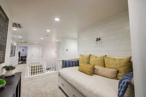 Sitting room with light carpet, recessed lighting, and an upstairs landing