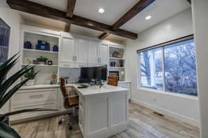 Office area featuring light wood finished floors, beamed ceiling, built in shelves, recessed lighting, and built in study area