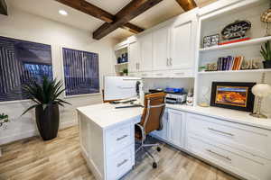 Office space with built in desk, beam ceiling, recessed lighting, and light wood-style floors