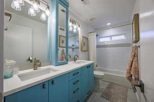 Bathroom with double vanity, shower / tub combo with curtain, and recessed lighting