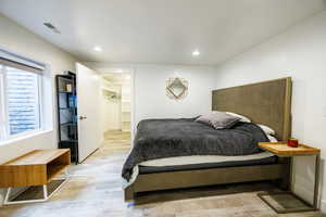 Bedroom featuring light wood finished floors, a spacious closet, and recessed lighting