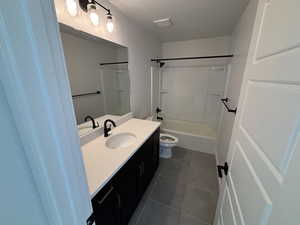 Bathroom featuring vanity, shower / bathtub combination, and dark tile patterned floors