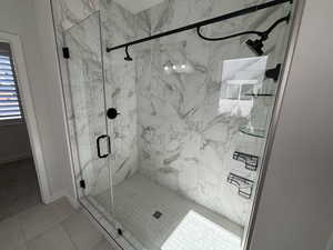 Bathroom featuring a marble finish shower and tile patterned flooring