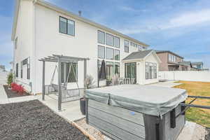 Rear view of property featuring a fenced backyard, a patio area, stucco siding, and a hot tub