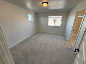 Unfurnished bedroom with light colored carpet and a textured ceiling