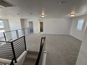 Unfurnished room featuring a textured ceiling, light colored carpet, and a smoke detector